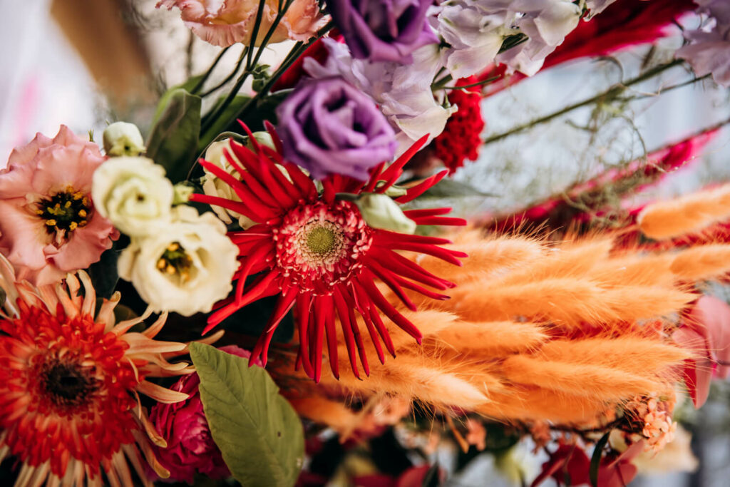gros plan d'un bouquet décoratif composé de fleurs fraiches et séchées de couleurs framboise, orange, rose mauve et saumoné lors d'un shooting d'inspiration mariage organisé à Emak Bakea à Bidart, lieu de reception de mariage en bord de mer
