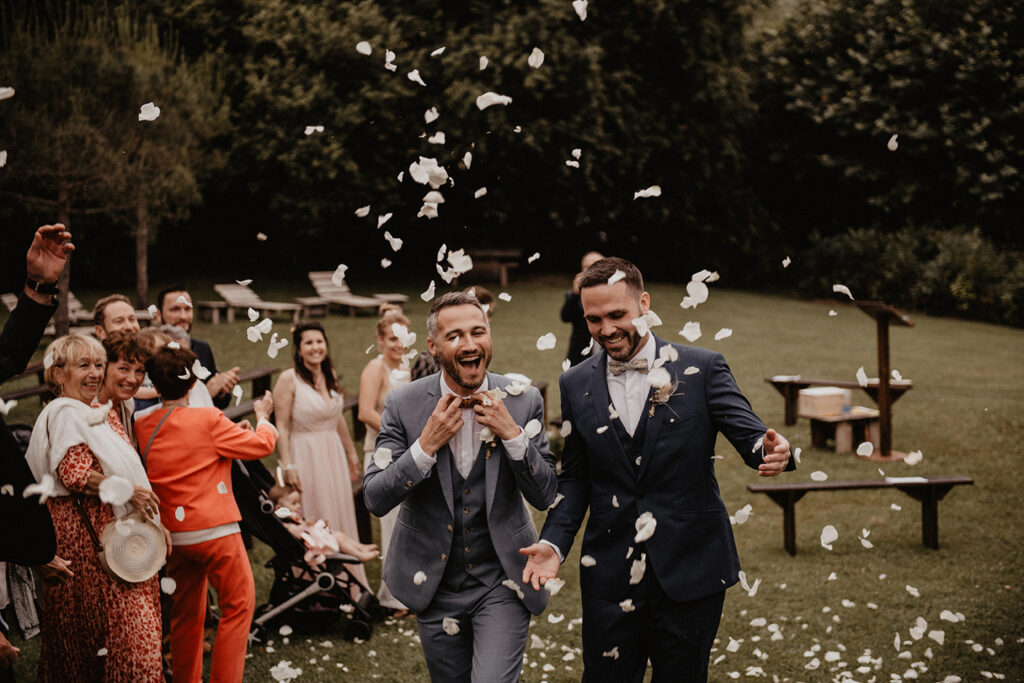 un couple de mariés d'hommes sort de leur cérémonie laïque lors du jeté de pétales de fleurs fraiches en vrac