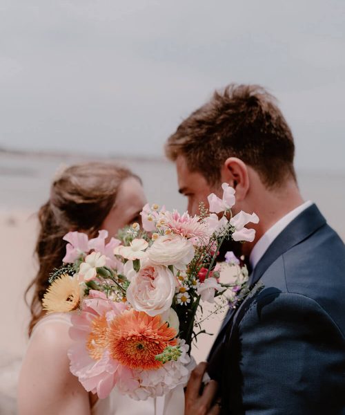 couple d'amoureux se regardant, caché par le bouquet de la mariée, sur la promenade de la plage de St Jean de luz