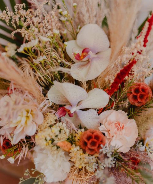 gros plan d'une composition florale d'un mélange de fleurs séchées et fleurs fraiches, sauvage et délicates, accompagné d'orchidées d'un mariage au Pays basque